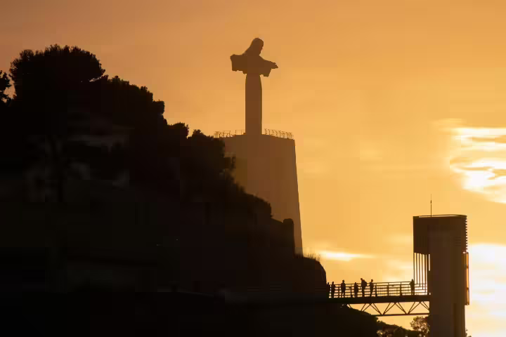 Majestic sunset view of iconic Cristo Rei statue in Lisbon, highlighting Arrábida & Sesimbra Day Trip's scenic beauty.