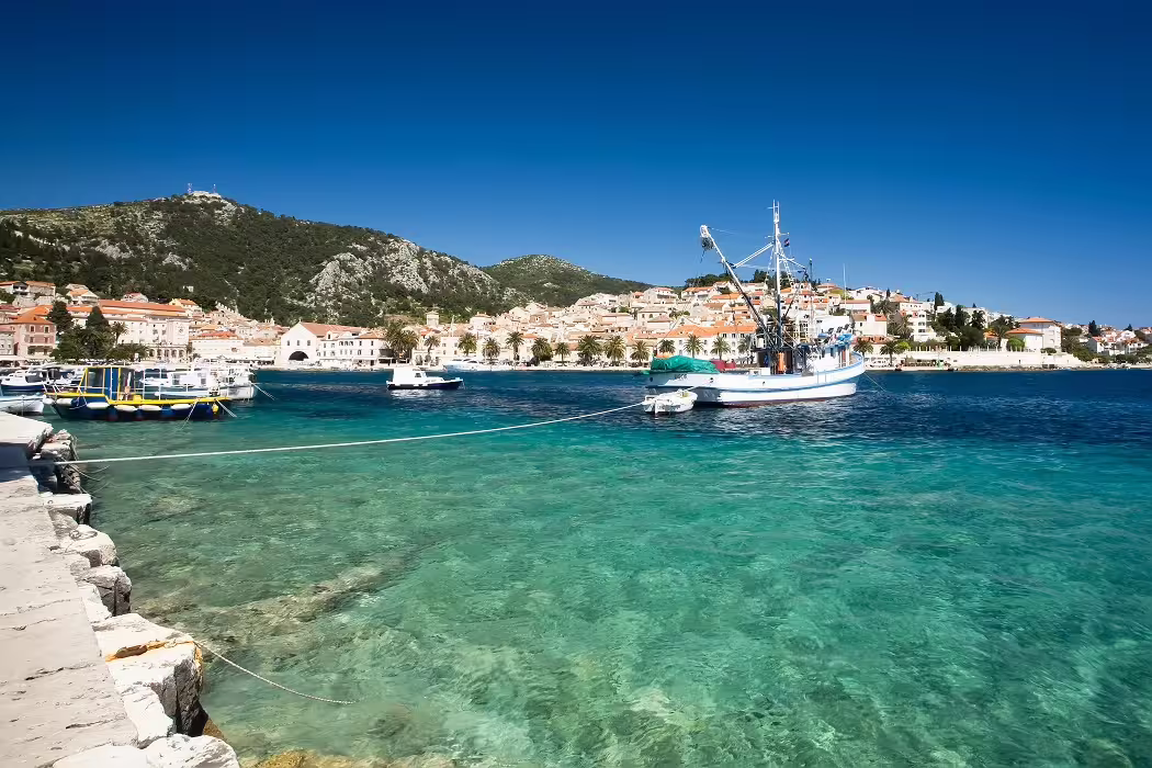 Crystal-clear Adriatic bay with fishing boat and island village, Croatia family island hopping adventure