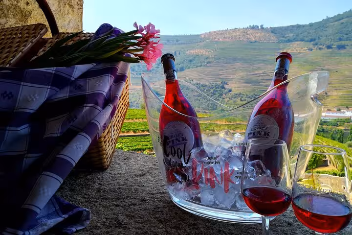 Croft Pink wine bottles chilling on ice with scenic Douro Valley terraced vineyard views during boat cruise tour
