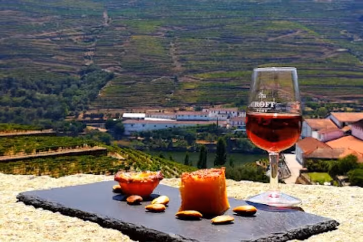 Croft Port wine glass with local cheese and almonds on slate board overlooking Douro Valley vineyards