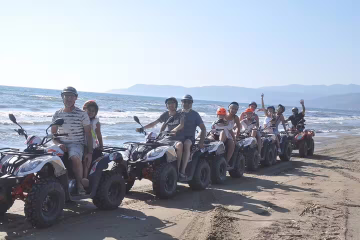 Group of cruise guests enjoying quad riding on the beach near Kusadasi, Turkey, with scenic coastal views.