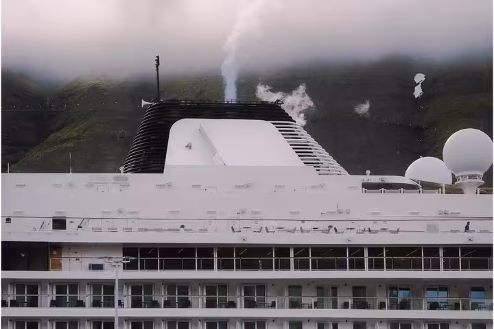 Large cruise ship docked near misty green mountains in the Westfjords of Iceland