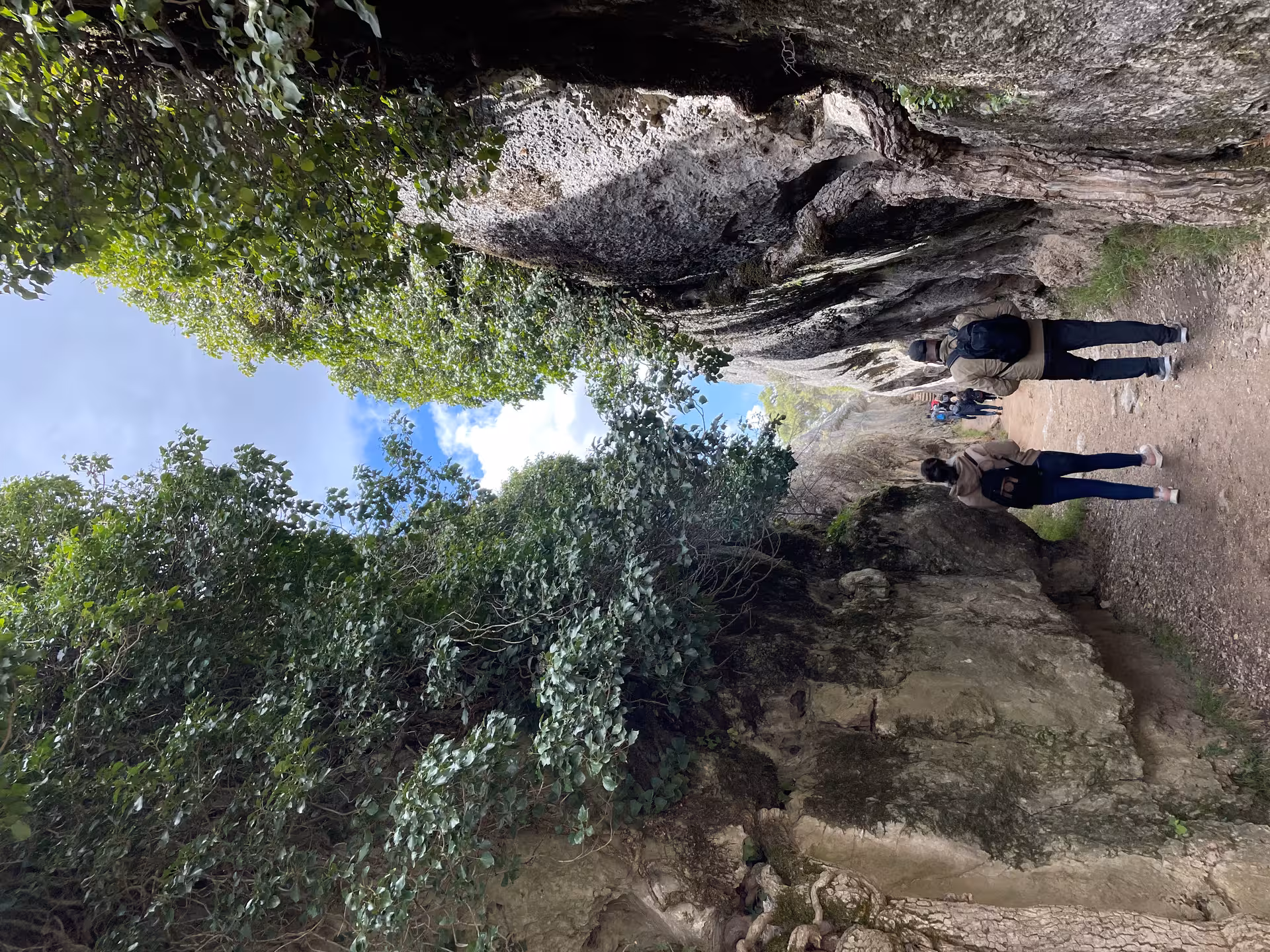 Hikers on a forest trail between limestone cliffs in Ciudad Encantada, Cuenca day tour from Madrid