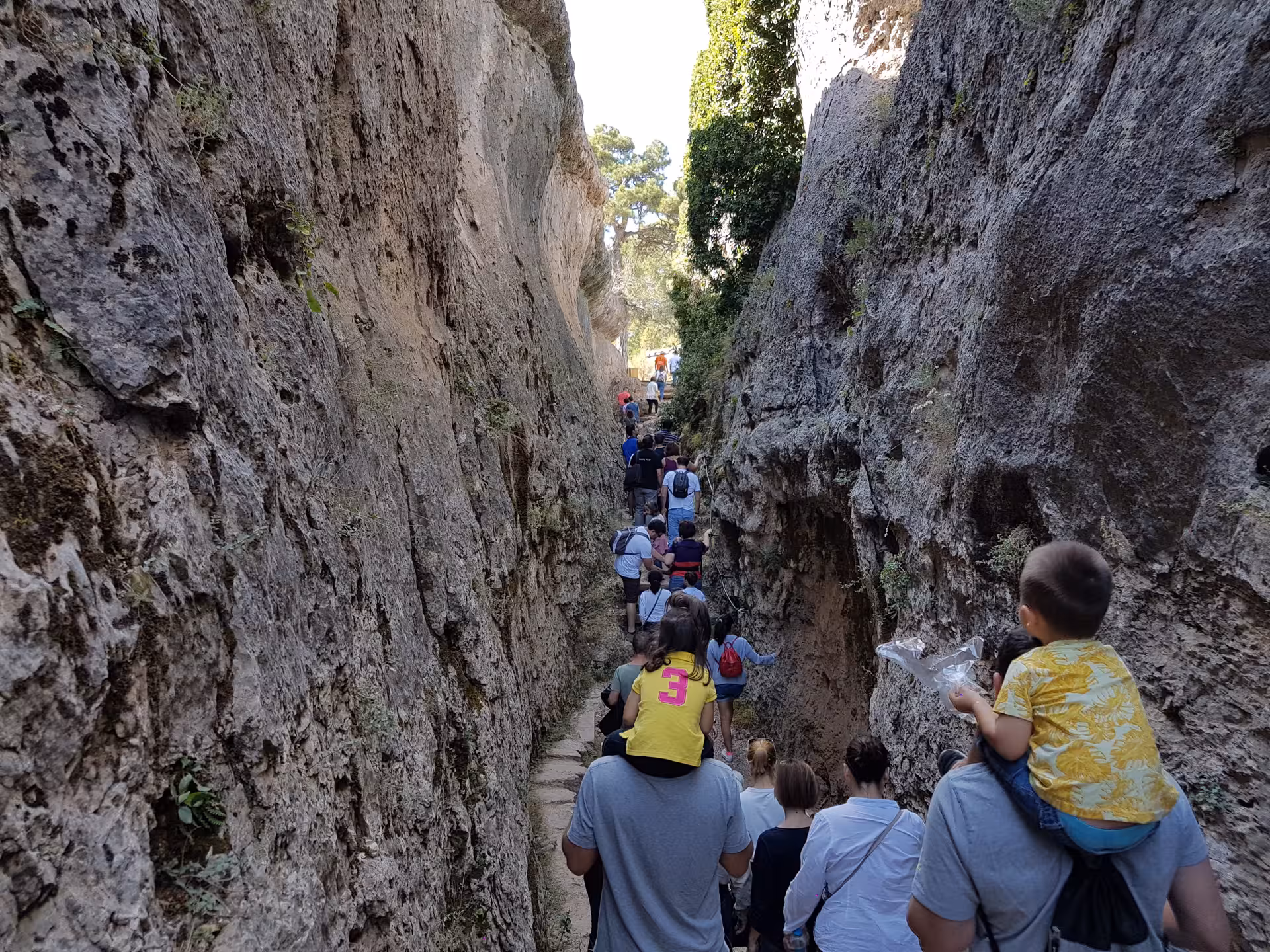 Visitors walking through a narrow rock corridor at Ciudad Encantada on the Cuenca day tour from Madrid
