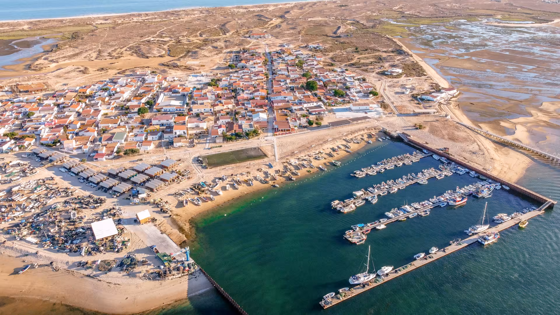 Aerial view of Culatra Island marina with boats docked along turquoise Ria Formosa channels on Olhao boat tour