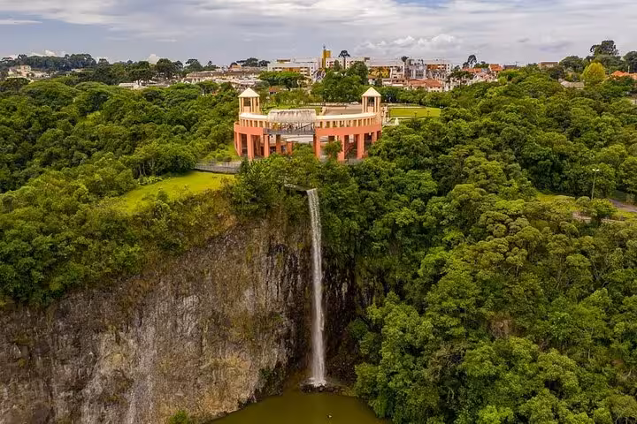 Aerial view of Curitiba's Tangua Park waterfall and observation deck surrounded by lush green landscape.