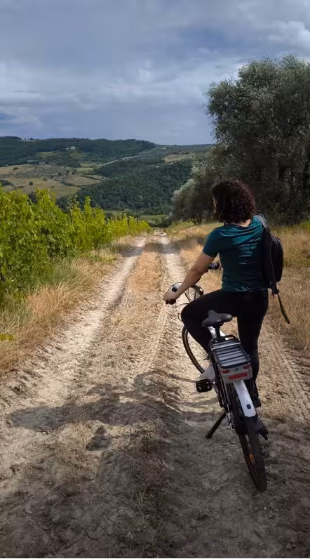 Cyclist enjoying a scenic dirt path through lush Tuscan hills on a self-guided bike tour.