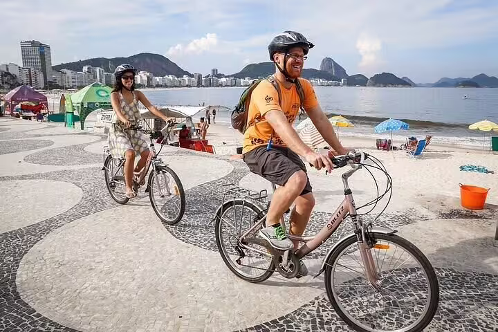 Happy cyclists exploring the famous Copacabana beachside path with stunning views of Rio's skyline and mountains.