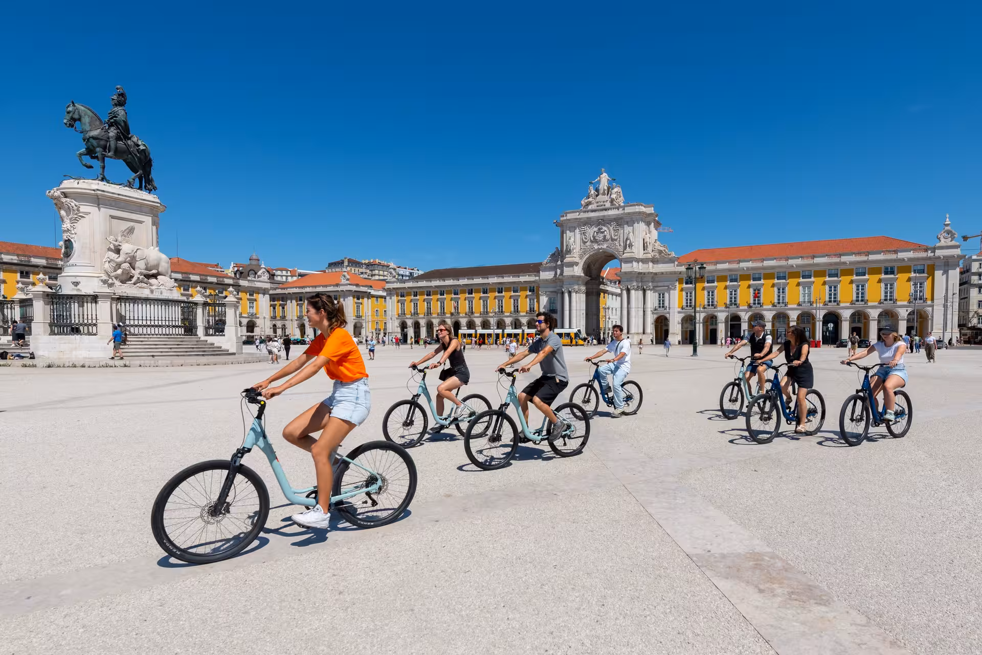 Cyclists explore Lisbon's Praça do Comércio on the River Light Bike Tour, with stunning views and rich history.