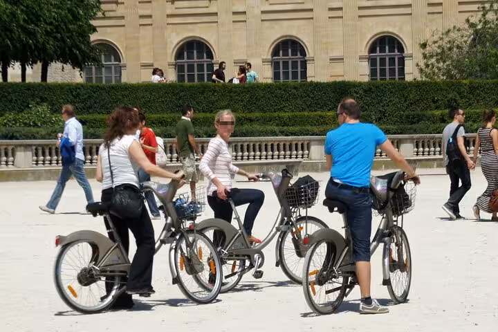 Cyclists with rental bikes near the Louvre Museum gardens, part of a Seine River bike tour in Paris