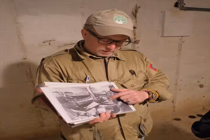 Tour guide examining black and white WWII photographs during D-Day beaches private tour from Le Havre