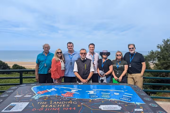 Tour group posing at Omaha Beach overlook with D-Day landing beaches map, Normandy, France