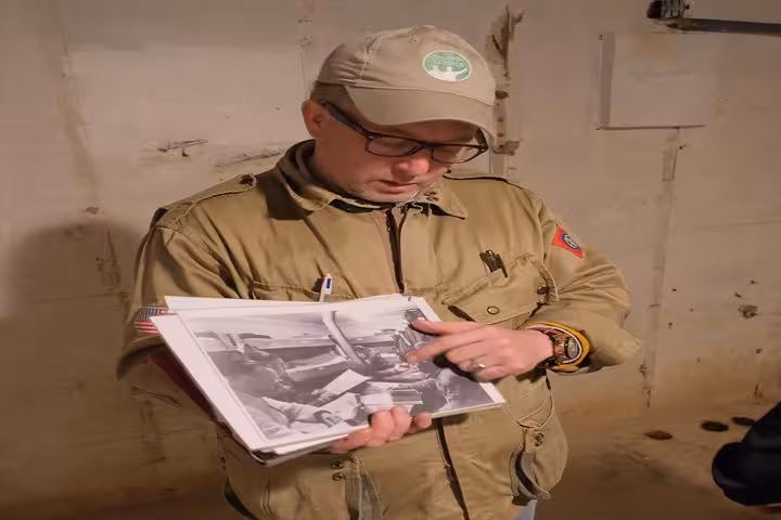 Tour guide examining WWII black and white photographs during D-Day Beaches private tour from Caen
