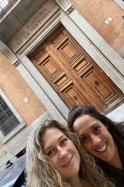Two women smiling for a selfie in front of the Real Academia de la Historia in Madrid