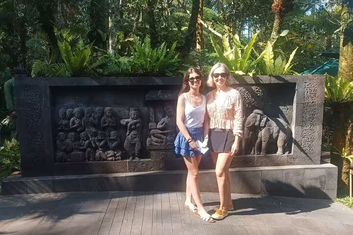 Travelers pose by carved stone memorial wall in Dachau, part of a private Munich and Dachau car tour