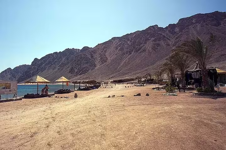 Sandy Dahab beach camp on the Red Sea with mountains, a stop on the 3 Pools snorkeling day trip from Sharm