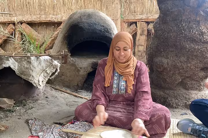 Local woman baking flatbread in a clay oven during Dahshur countryside farmer day experience in Egypt