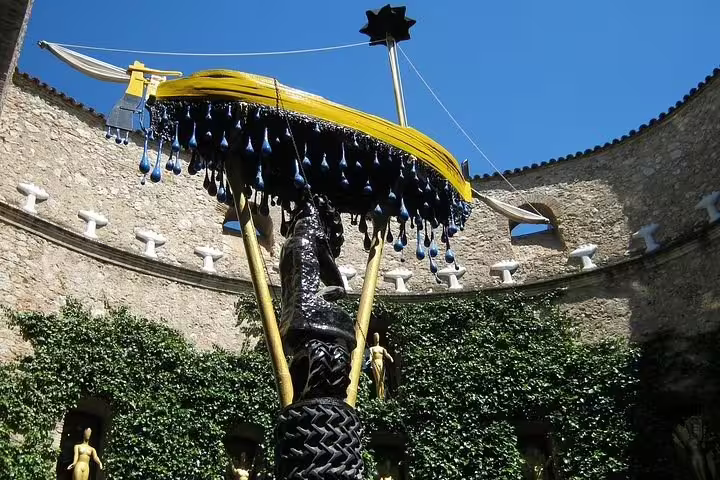 Surreal sculpture at Dalí Museum courtyard in Costa Brava, showcasing unique art elements under a blue sky.