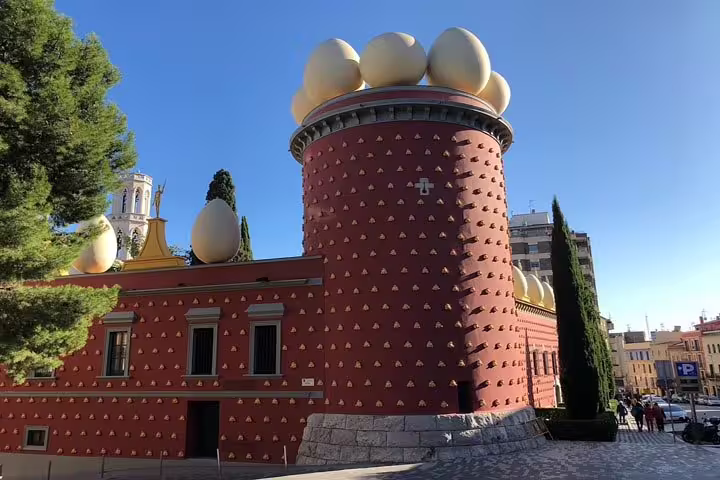 Sunny day at the Dalí Theatre-Museum, featuring its distinctive egg-topped tower and artistic red brick exterior.