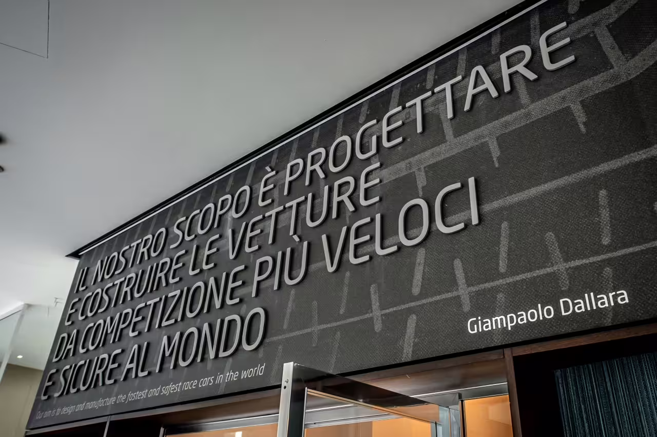 Inspirational quote by Giampaolo Dallara on designing the fastest, safest race cars at the Dallara Academy entrance.