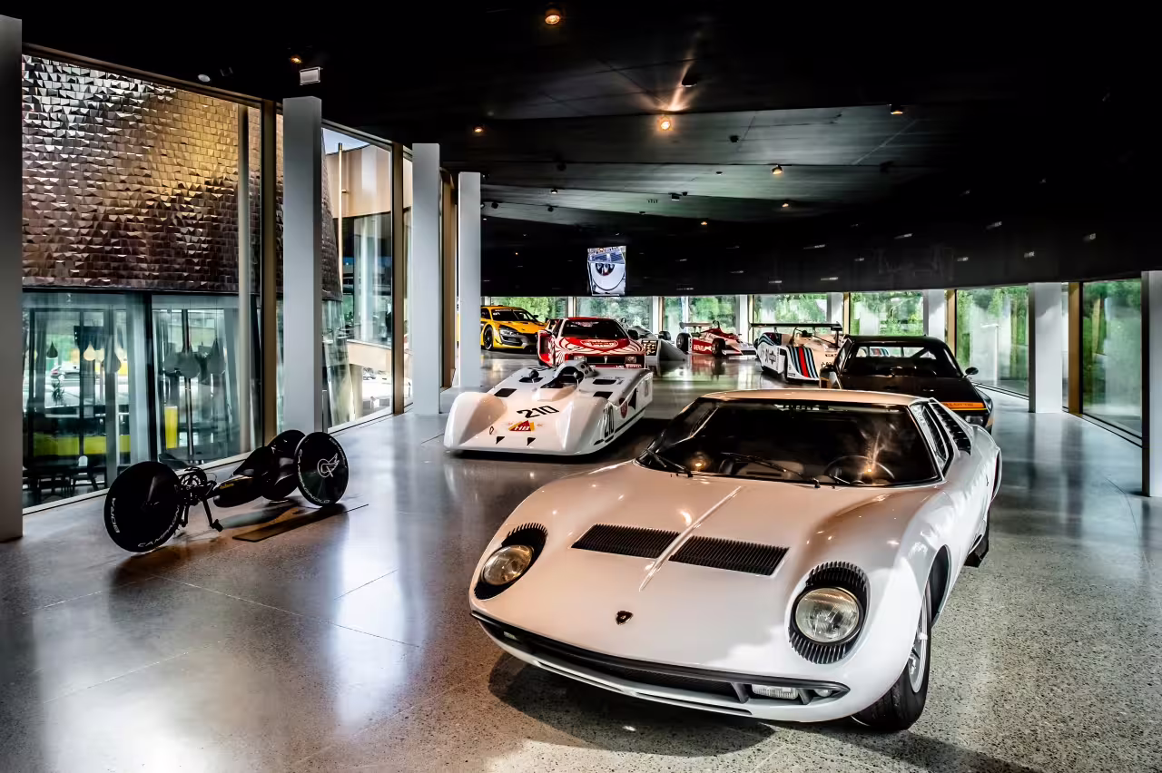 Exhibition of classic and modern race cars inside Dallara Academy, highlighting motorsport heritage in Parma.