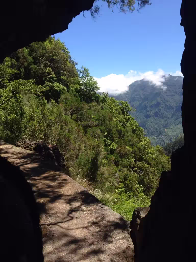 Scenic mountain view from cave entrance on The Dark Hike, surrounded by lush greenery.
