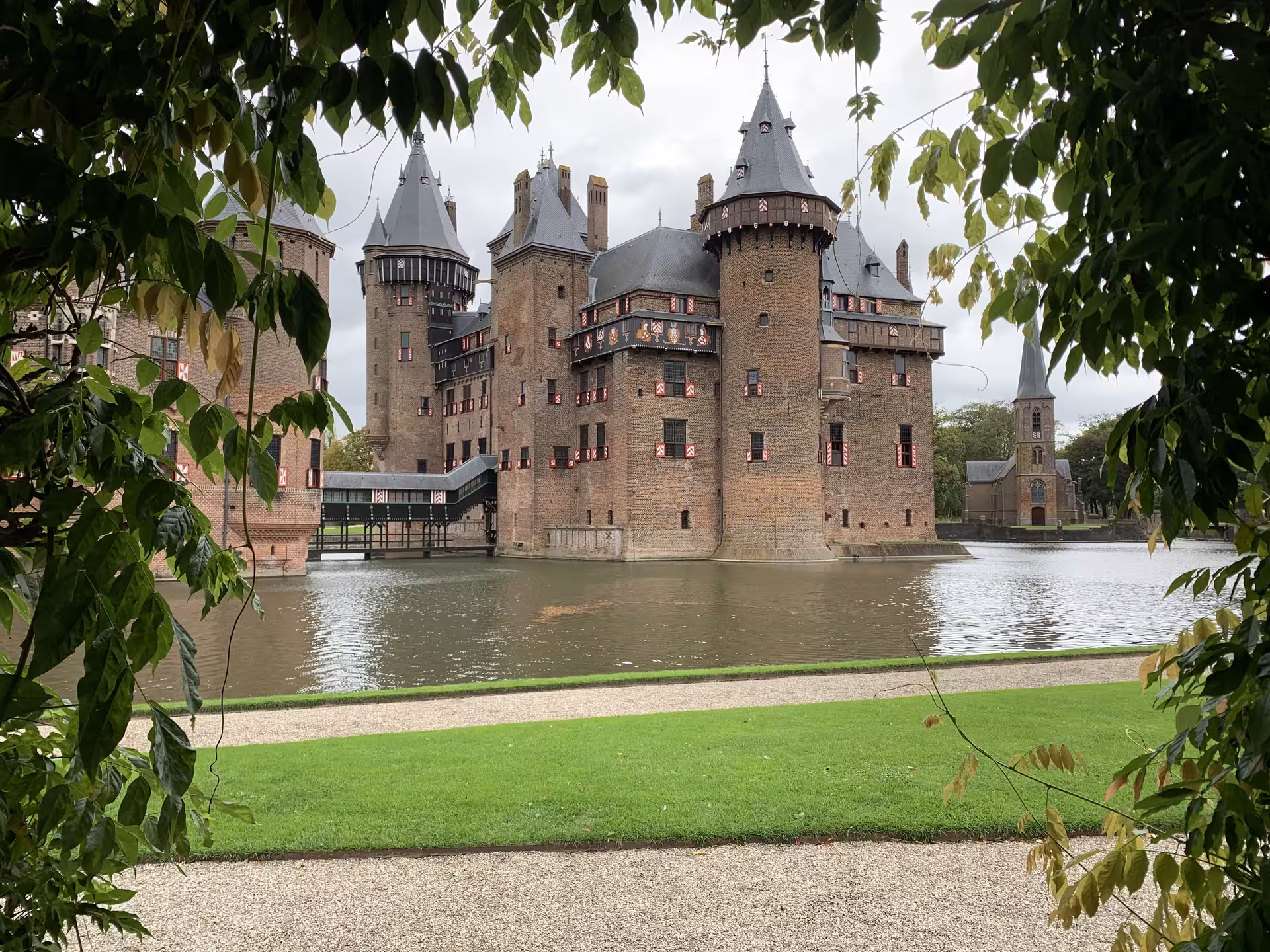 De Haar Castle moat view framed by leafy trees, scenic stop on a private tour from Amsterdam to Utrecht