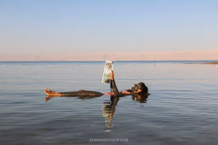 Tour guest floating in the Dead Sea reading a newspaper, classic experience on Egypt Jordan Jerusalem trip