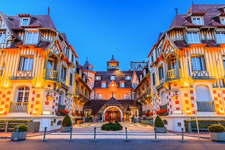 Grand Norman-style hotel facade in Deauville illuminated at dusk with ornate half-timbered architecture