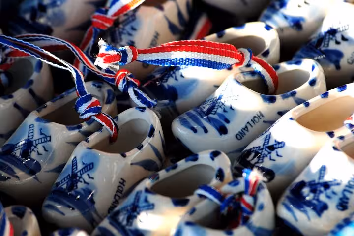 Mini Delft blue clogs souvenirs with Dutch flag ribbons, shopping stop on Rotterdam Delft The Hague tour