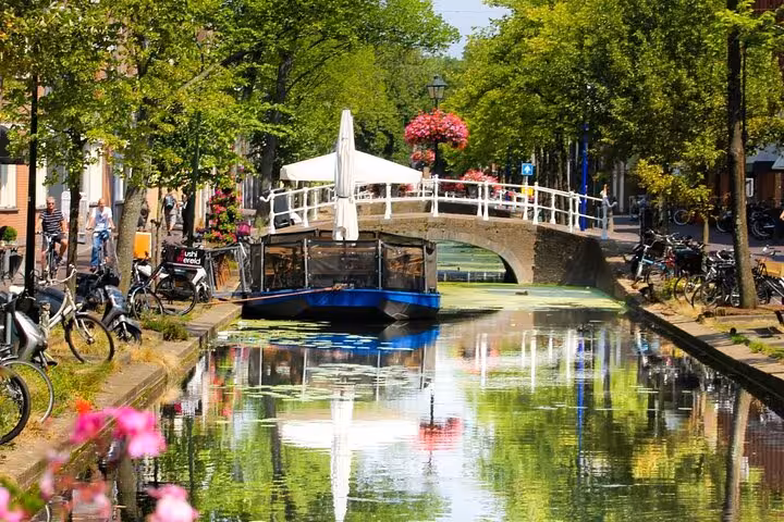 Delft canal with arched bridge, bikes and boat, seen on private day tour from Amsterdam to Rotterdam and The Hague