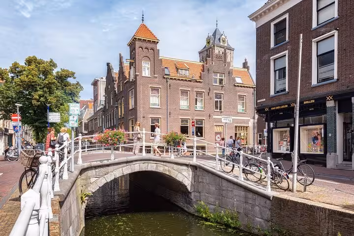 Stone bridge over a canal in Delft with historic Dutch brick buildings and bicycles