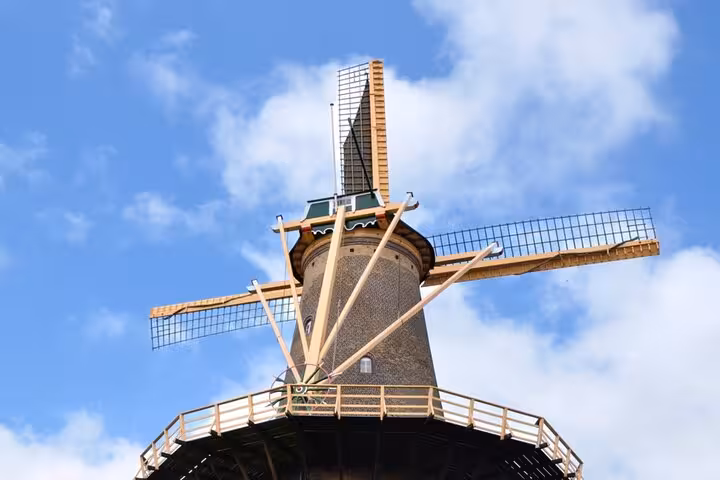 Historic Dutch windmill with wooden sails against blue sky in Delft, Netherlands
