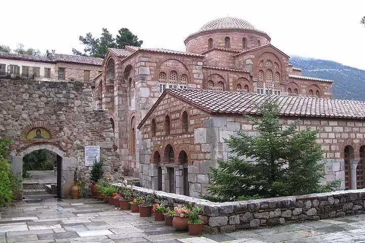 Monastery courtyard at Delphi with Byzantine stone arches and flower pots, stop on Delphi Meteora 2-day tour