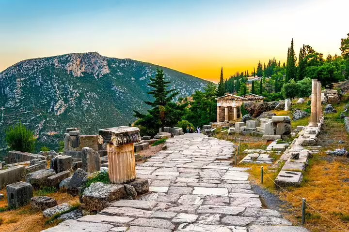 Ancient stone path through Delphi ruins at sunset with Mount Parnassus backdrop on a Delphi full day tour