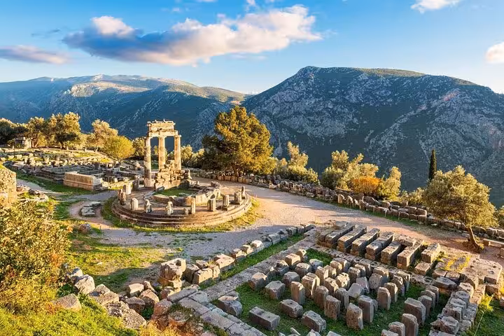 Sunlit Delphi sanctuary ruins and Tholos of Athena Pronaia, scenic private day trip from Athens Greece