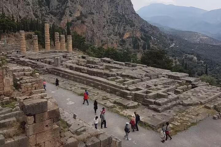 Visitors explore the Temple of Apollo ruins in Delphi on a private guided day tour from Athens, Greece