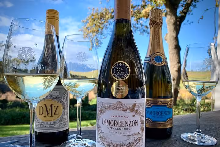 Close-up of DeMorgenzon wine bottles and glasses on an outdoor table, showcasing Stellenbosch's fine wines.