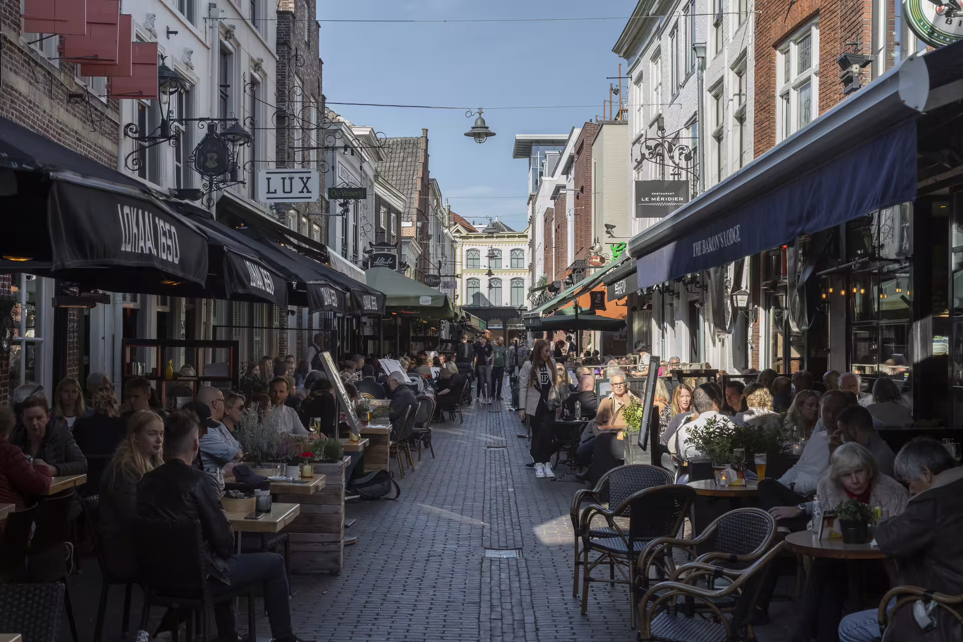 Busy Den Bosch historic shopping street with terrace cafes, featured on 1-day walking tour audioguide