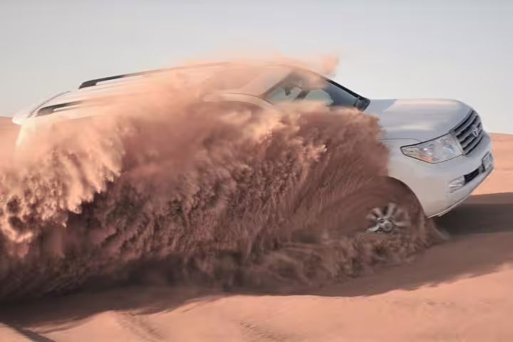 4x4 vehicle kicking up sand during an exhilarating desert safari adventure, perfect for morning to sunset tours.