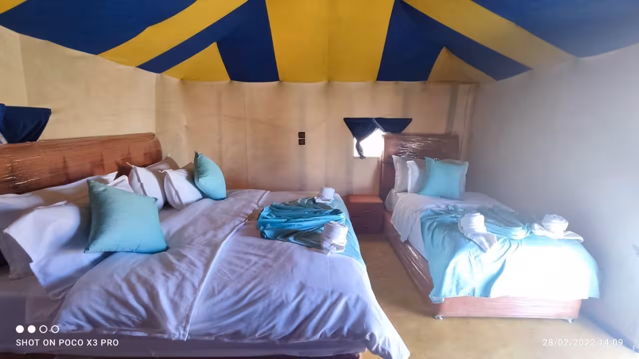 Spacious desert tent with comfortable beds and colorful canopy on Fes to Merzouga tour.
