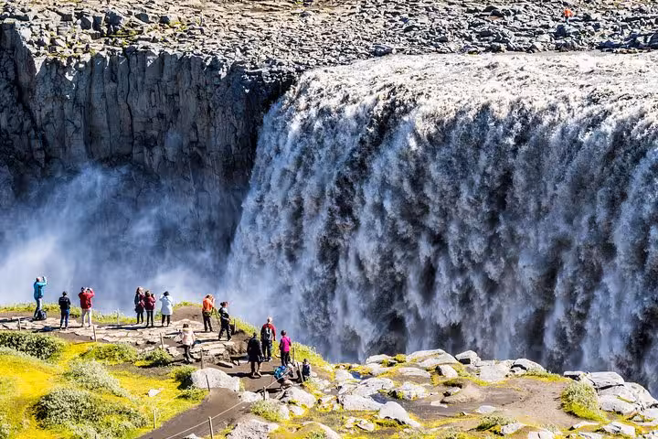 Visitors capturing the powerful flow of Dettifoss waterfall during the Diamond Circle Day Tour in Iceland.
