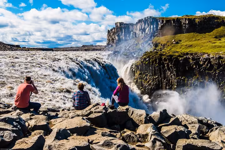 Tourists enjoying the breathtaking view of Dettifoss waterfall on the Diamond Circle Day Tour from Akureyri.
