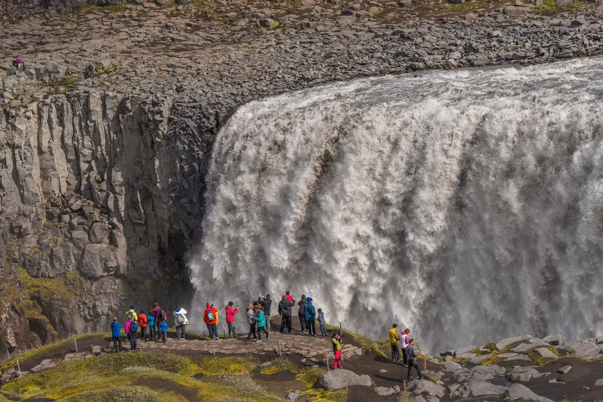 Tourists admiring the powerful Dettifoss waterfall on the 9-day Complete Iceland Circle self-drive tour.