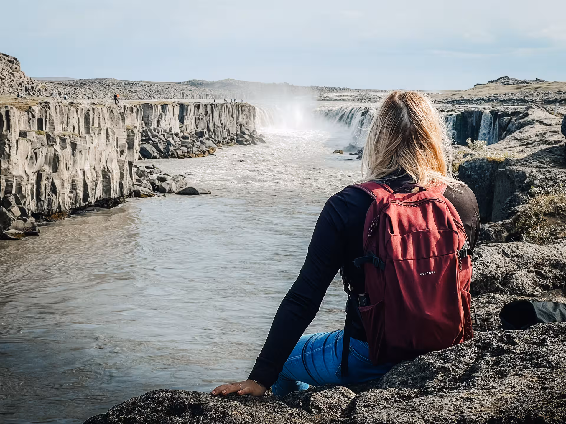 Traveler overlooking Dettifoss waterfall canyon on Iceland Diamond Circle tour, rugged basalt cliffs and mist