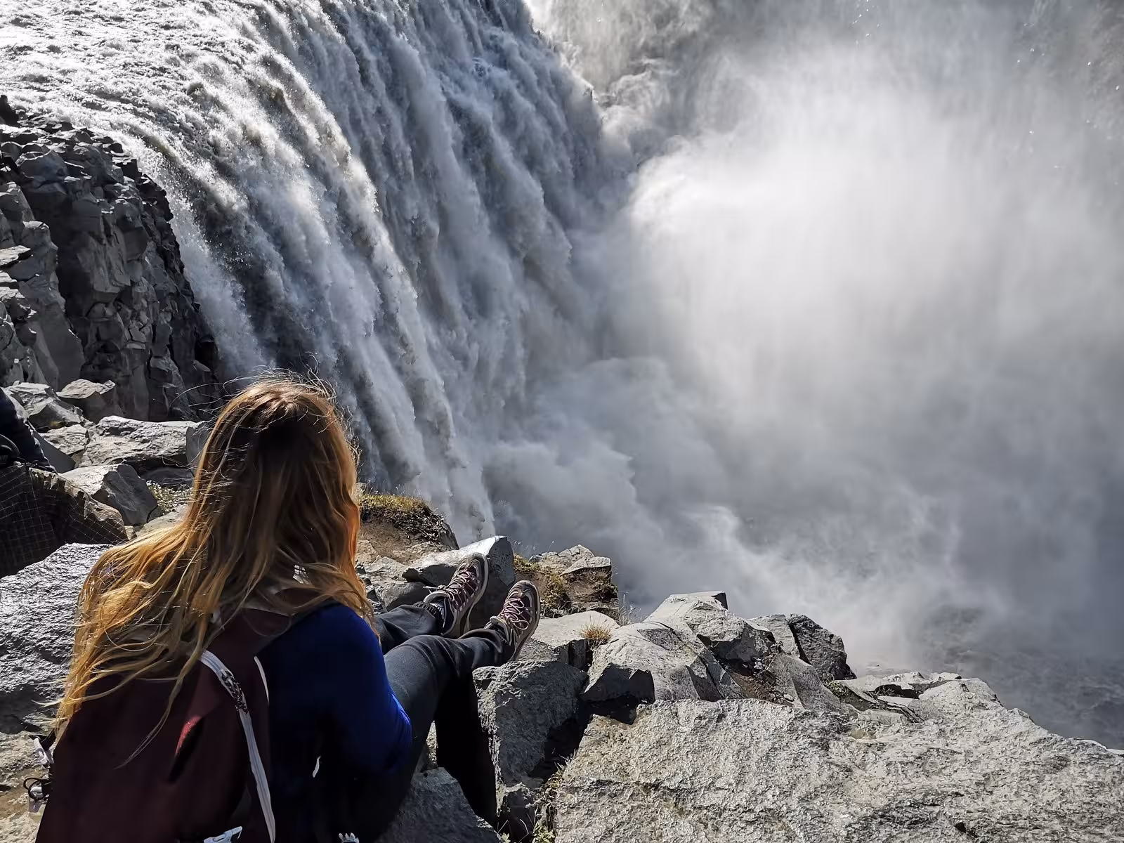 Traveler enjoying the breathtaking view of Dettifoss waterfall on a small group tour in Iceland.