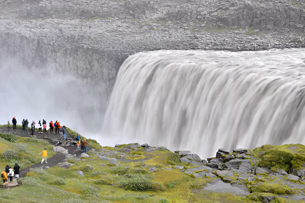 Tourists viewing massive Dettifoss waterfall cascading over rocky cliffs near Lake Myvatn, Iceland