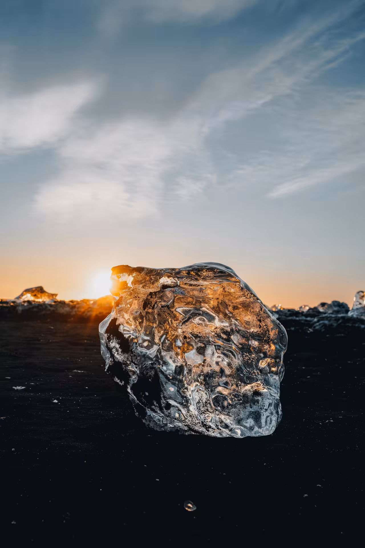 Ice chunk on black sand beach at sunset, Diamond Beach Iceland glacier lagoon