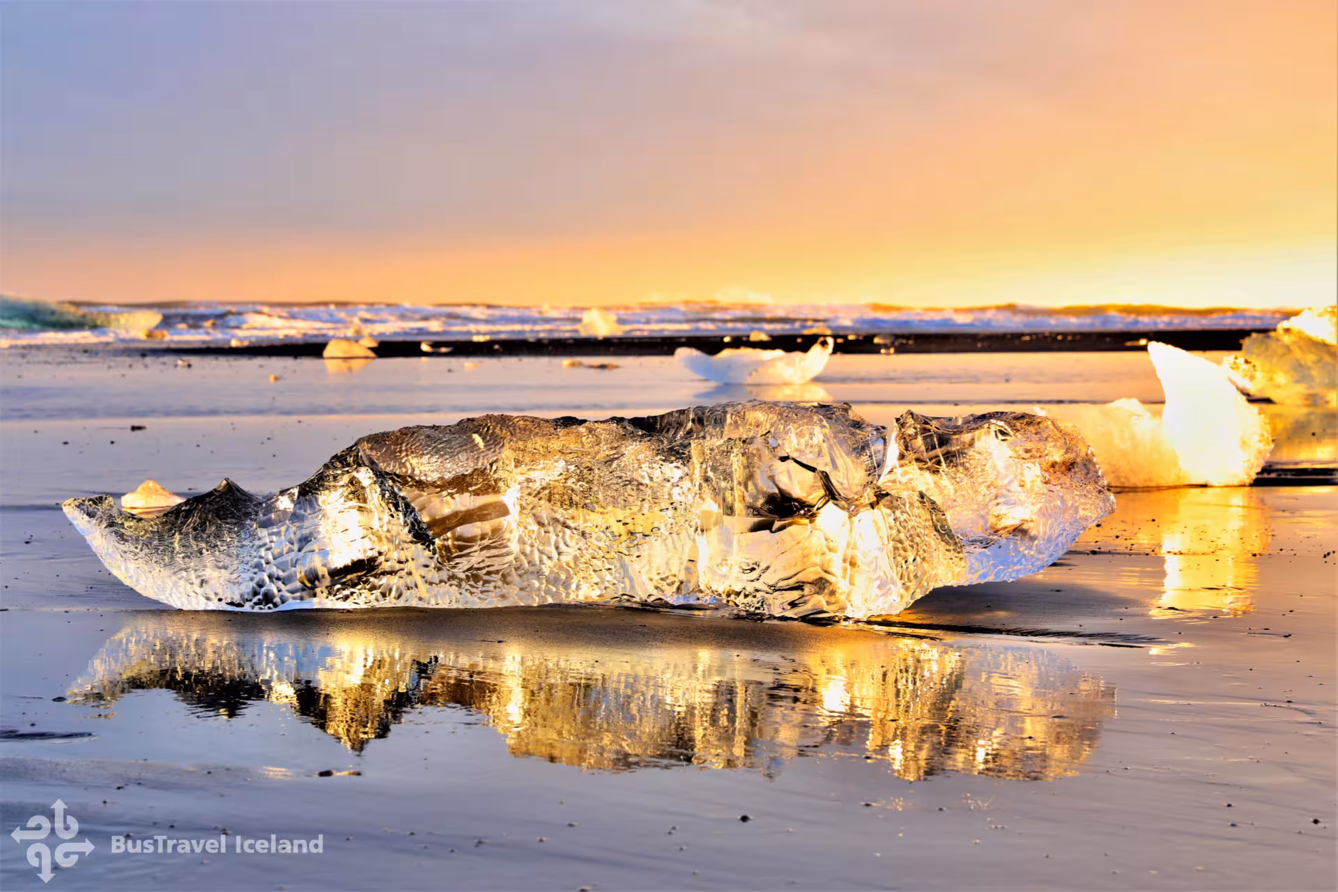 Glowing ice chunk on black sand Diamond Beach Iceland at golden sunset with glacier lagoon in background