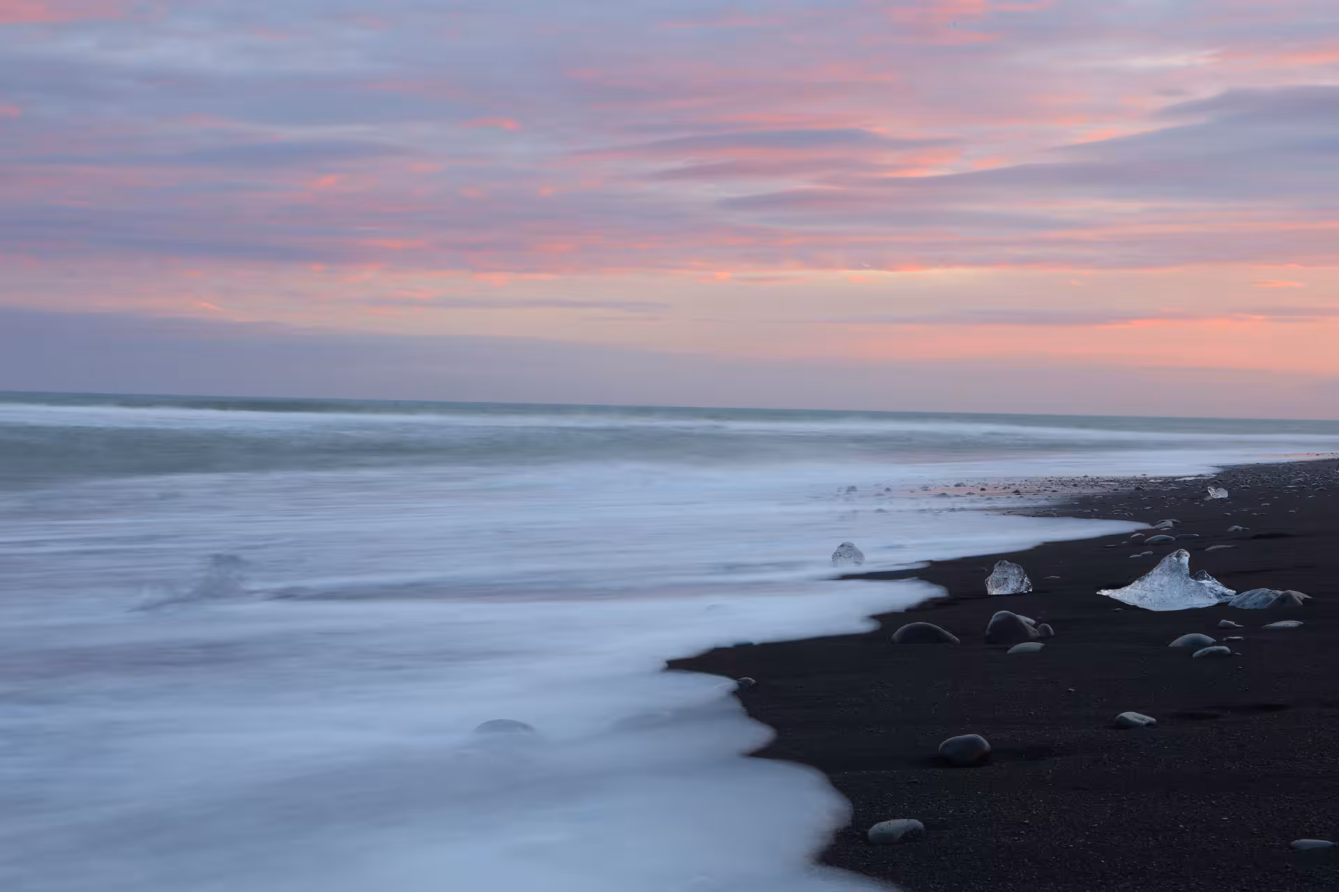 Ice chunks on Diamond Beach black sand shore at sunset near Jokulsarlon Glacier Lagoon, Iceland